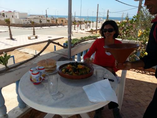 Tan-Tan Plage的住宿－Hotel Canarias Sahara，坐在餐桌旁吃一碗食物的女人