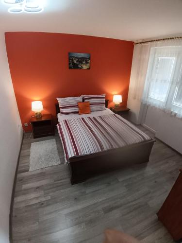 a bedroom with orange walls and a bed with two lamps at Apartman Drenovac in Slunj