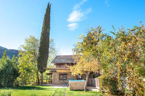 a house with a large tree in the yard at Comfortable lakeside house! in Güéjar-Sierra