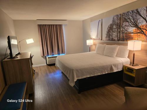 a hotel room with a bed and a television at Days Inn & Suites by Wyndham Cuba in Cuba