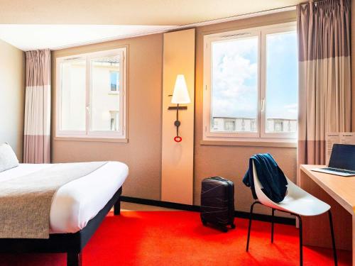 a hotel room with a bed and a desk and window at Hôtel Ibis Cognac Centre in Cognac