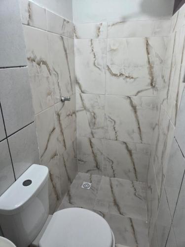 a bathroom with a white toilet and marble walls at Hotel Goldem Park in Brasília