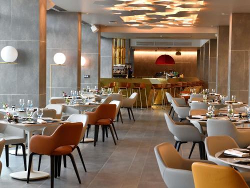 ein Restaurant mit Tischen und Stühlen und einer Bar in der Unterkunft Pullman Abidjan in Abidjan