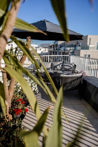 a balcony with two chairs and an umbrella at Central Penthouse with massive terrace in San Ġwann