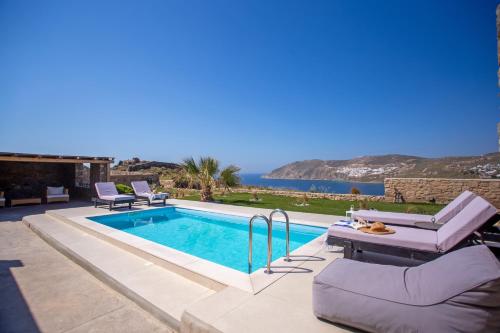 a swimming pool with two lounge chairs and a table at South Star private Mini Villa in Mikonos