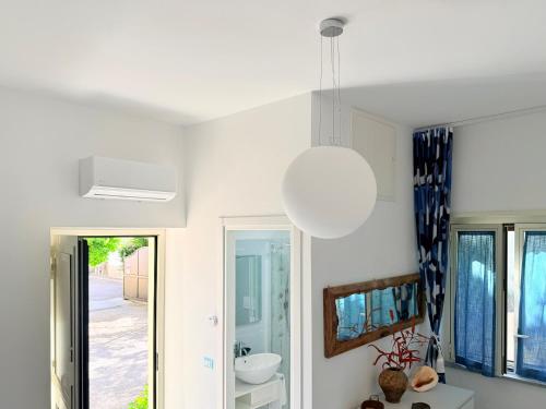 a white room with a mirror and a light fixture at B&B Edda Maison Centralissimo sul Lungomare con Posto Auto e Giardino Privato in Sperlonga
