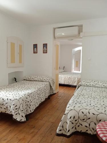 three beds in a room with wooden floors at Casa do Arco da Praça in Elvas