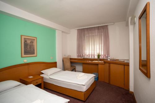 a hotel room with two beds and a desk at Hotel Ferijalac in Sarajevo