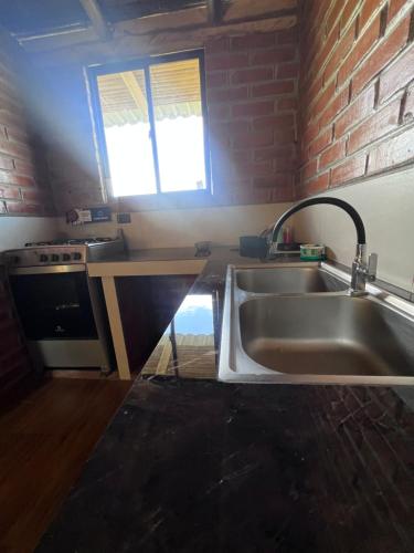 a kitchen with a sink and a brick wall at Refugio del venado familiar in Cotacachi