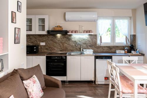 a kitchen with a sink and a table with a couch at Róna Fénye Vendégház in Sándorfalva