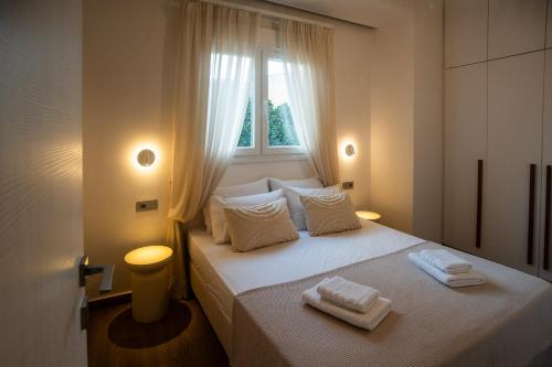 a bedroom with a white bed with two towels on it at Cerro Fine Living in Ermoupoli