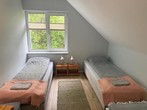 a attic bedroom with two beds and a window at Pokoje przy rzece in Supraśl