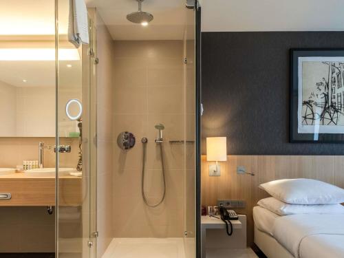 a bathroom with a shower and a bed and a sink at Mercure Amsterdam City Hotel in Amsterdam