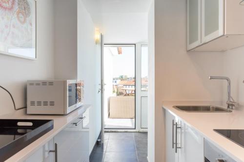 a white kitchen with a sink and a microwave at Park View Central Apartment in Cascais in Cascais