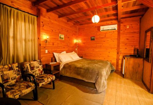 a bedroom with a bed and two chairs in a room at Café e Cabanas Lenha no Fogo in Urubici