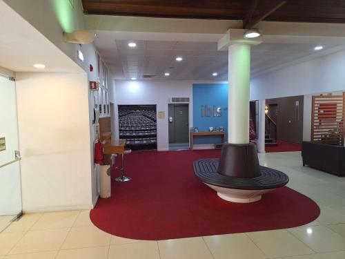 a lobby with a hat sitting on a red rug at Hotel ibis Setubal in Setúbal