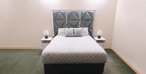 a bedroom with a large bed with two night stands at The Vine House in Harare