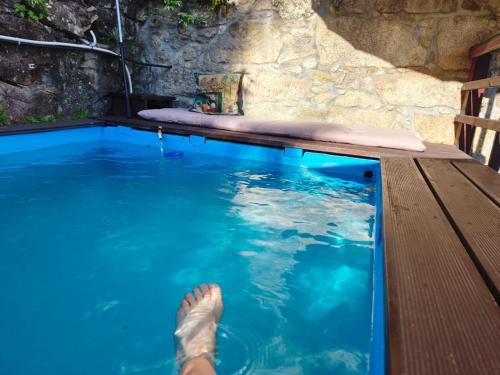 a persons feet in the water next to a swimming pool at Casa da Maria Gata in Sever do Vouga