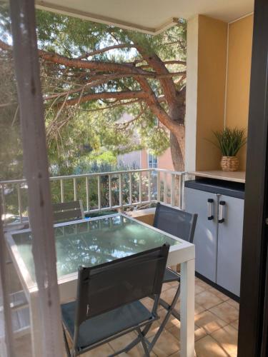 a table and chairs on a balcony with a tree at Coudou Beach T2 cosy à 2 pas de la mer in Six-Fours-les-Plages