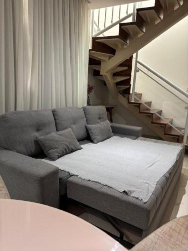 a couch in a living room with a staircase at Santos Unique 2701 Jacuzzi & Sea View Duplex in Santos