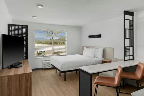 a bedroom with a bed and a desk and a television at StudioRes by Marriott Leland in Leland