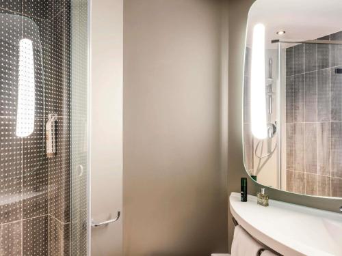 a bathroom with a shower and a sink and a mirror at ibis Paris Coeur d'Orly Airport in Orly