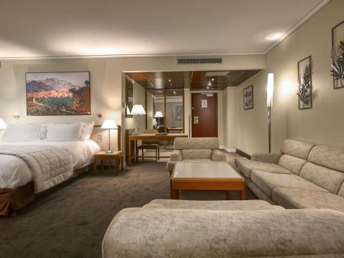 a hotel room with a bed and a living room at Sofitel Algiers Hamma Garden in Alger