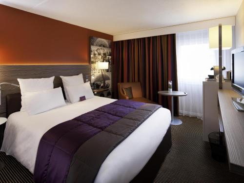 a hotel room with a large bed and a television at Mercure Chambéry Centre in Chambéry