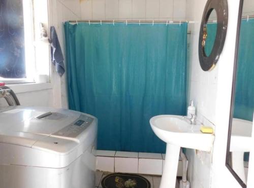 a bathroom with a blue shower curtain and a sink at Wind & Way Hostel in Valparaíso