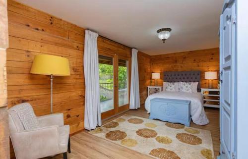 a bedroom with wooden walls and a bed and a chair at Blue Mountains Cabin in Boquete