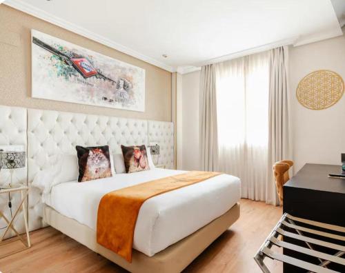 a bedroom with a large white bed and a desk at Hotel Suites Feria de Madrid in Madrid