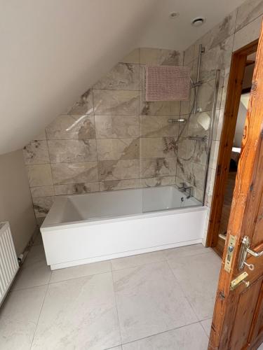 a white bath tub in a bathroom with a stone wall at Kilmurry heights in Kenmare