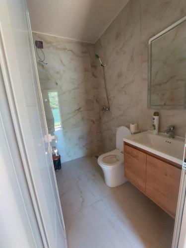 a white bathroom with a toilet and a sink at Villa Sajmo in Koman