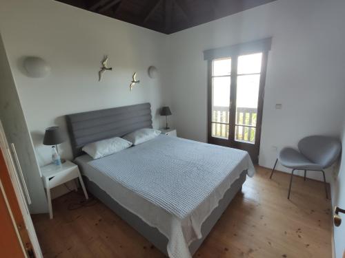 a white bedroom with a bed and a window at Villas garden&pool in Afitos