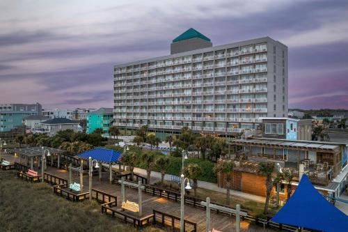 a large white building with benches in front of it at Courtyard by Marriott Carolina Beach Oceanfront in Carolina Beach