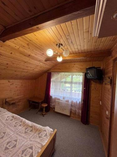 a bedroom with a bed and a window and a television at Котедж Криниченька in Yaremche