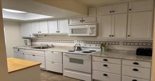 a kitchen with white cabinets and white appliances at Serene Florida Oasis in Inverness