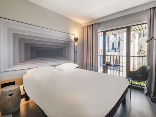 a bedroom with a large white bed and a window at ibis Saint Quentin Centre Basilique in Saint-Quentin