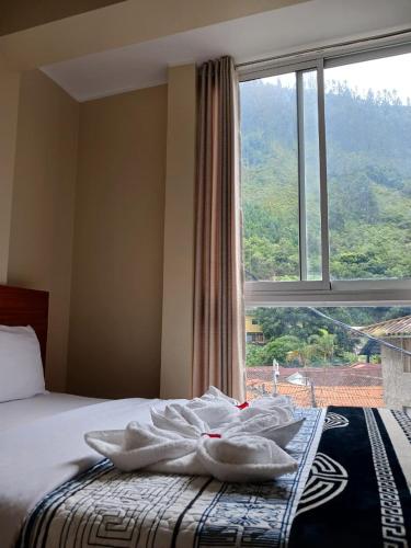 a bed with towels on it with a large window at Haylli Café Oro Hotel in Santa Teresa