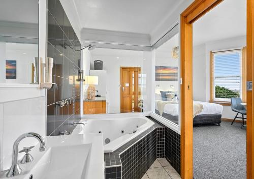 a bathroom with a tub and a bedroom with a bed at Stanley Seaview Inn in Stanley