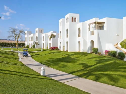 a large white building with a green lawn at Hotel Novotel Sharm El-Sheikh in Sharm El Sheikh