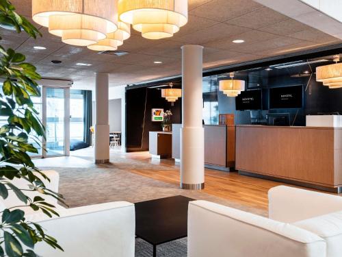 an office lobby with white chairs and a reception desk at Novotel Belfort Centre Atria in Belfort