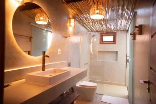 a bathroom with a sink and a toilet and a mirror at Pousada Villa Tainá - Arraial d'Ajuda, Bahia in Arraial d'Ajuda
