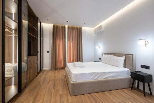 a bedroom with a large white bed and wooden floors at Aria Luxury Villa 2 in Dhërmi