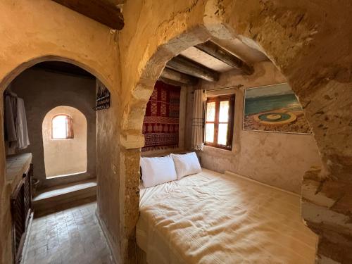 a bedroom with a bed in a stone room at Tenasbook Jnen Rayhane in Midoun