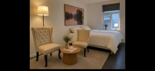 ein Schlafzimmer mit einem Bett, zwei Stühlen und einem Tisch in der Unterkunft Centrumrooms in Mosjøen