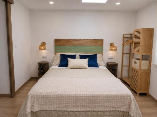 a bedroom with a large bed with blue pillows at APARTAMENTOS LA CAPILLA in Villanueva de Arosa