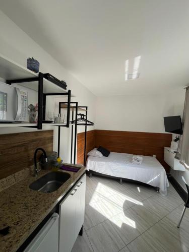 a kitchen with a sink and a bed in a room at Vaccani Apart in Macaé
