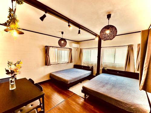 a room with two beds and a table in it at Between Kyoto & Osaka 渚南 駅徒歩3分 in Hirakata