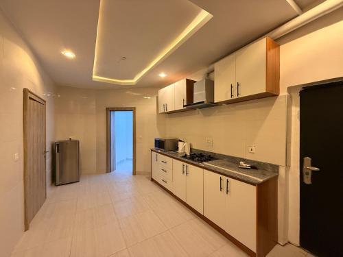 a kitchen with white cabinets and a stainless steel refrigerator at Luxury 3 Bedroom Duplex Service Aparment in Abuja in Abuja